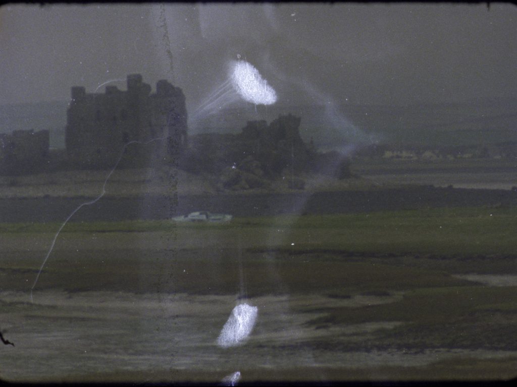 Still of Piel Castle with white boat on green salt marsh in the foreground